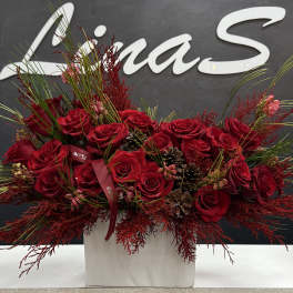 Red rose arrangement in a white box with pinecones and ribbon