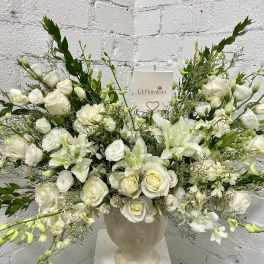 White floral arrangement in a cream urn vase