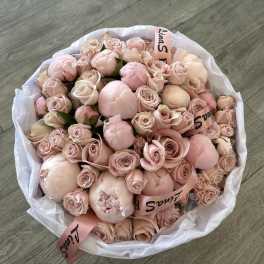 Large bouquet of pale pink roses and peonies wrapped in white paper