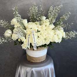 Cream rose arrangement in a woven basket with tall airy filler stems
