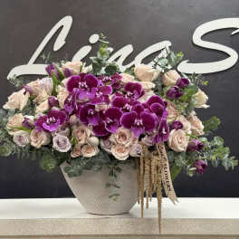 Large bouquet of purple orchids and pale roses in a textured white vase