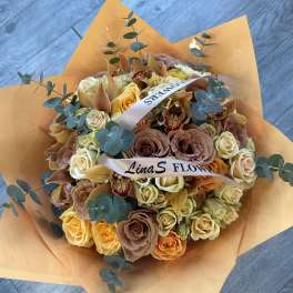 Bouquet of peach and cream roses with orchids and eucalyptus in orange wrap