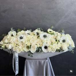 Long white floral arrangement with roses and anemones in a low container