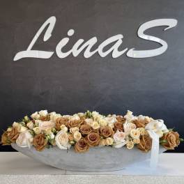 Long low arrangement of cream and tan roses in a shallow gray container