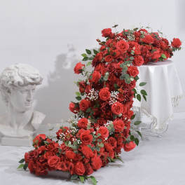Large cascading arrangement of red roses with greenery on a white pedestal