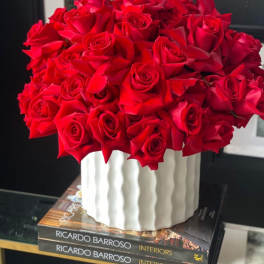 A bouquet of red roses in a white ribbed vase