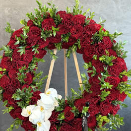 Heart-shaped wreath of red roses with white orchids on a wooden easel