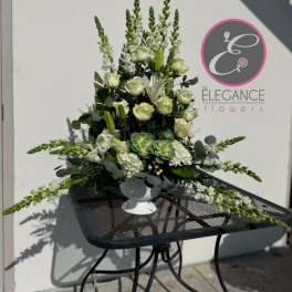 Tall white and green floral arrangement in a white pedestal vase