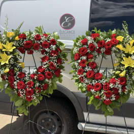 Two red rose wreaths with yellow lilies on black stands