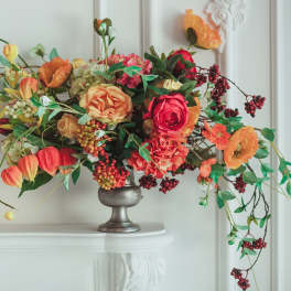 Arrangement of orange and pink flowers in a silver vase