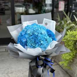 Bright blue hydrangea bouquet wrapped in gray paper with black ribbon