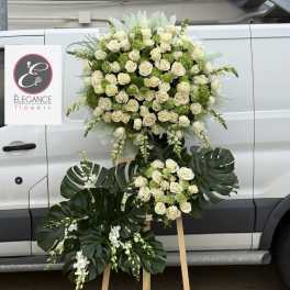 Large white rose and green floral standing arrangement on an easel