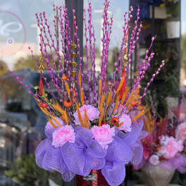 Tall purple floral arrangement in a red vase with pink blooms