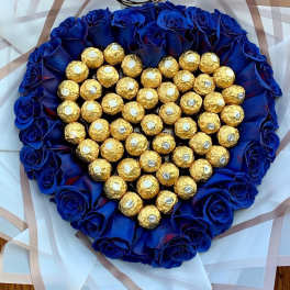 Heart-shaped bouquet of blue roses surrounding gold-wrapped chocolates