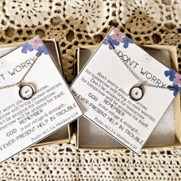 Two gift boxes with scripture cards and necklaces on a crocheted background