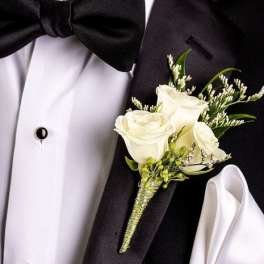 White rose boutonniere pinned to a black tuxedo jacket