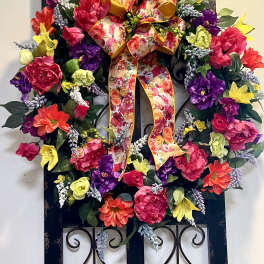 Colorful floral wreath with a large patterned bow on a black frame