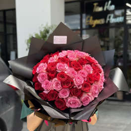Large bouquet of red and pink roses wrapped in dark paper