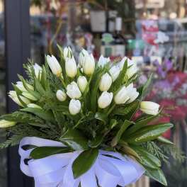 White tulip bouquet in a clear glass vase with a lavender ribbon