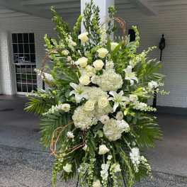 Large white floral standing spray on an easel with roses and lilies
