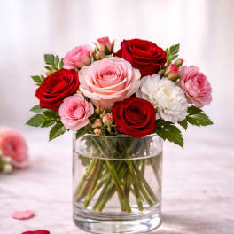 Pink and red roses with white blooms in a clear glass vase