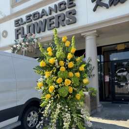Tall standing floral spray with yellow roses and white trailing blooms