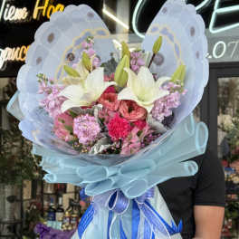 Bouquet of white lilies and pink flowers wrapped in blue paper