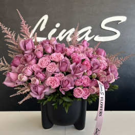 Pink rose bouquet in a black vase with a ribbon