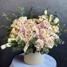 Cream rose and pink orchid arrangement in a white vase