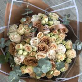 Bouquet of peach and cream roses with eucalyptus in brown wrap