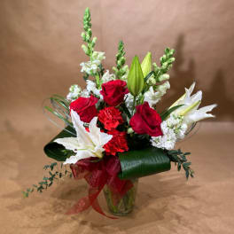 Red roses and white lilies in a glass vase with a red ribbon