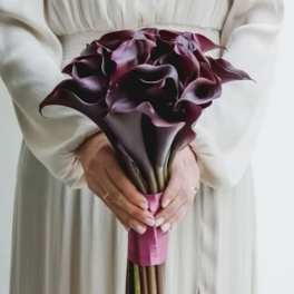 Bouquet of dark purple calla lilies held in both hands
