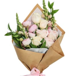 Bouquet of pale pink and cream roses wrapped in brown paper
