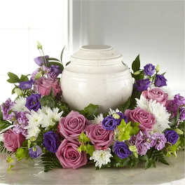 Purple and pink roses arranged around a white urn