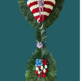 Heart-shaped floral tribute in red, white, and blue with ribbon accents