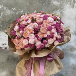 Large bouquet of pink and peach roses wrapped in brown paper with pink ribbons