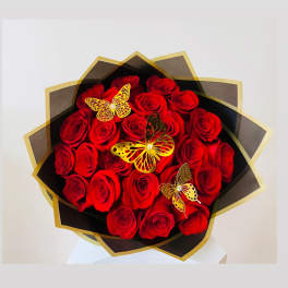 Bouquet of red roses wrapped in black and gold paper with butterfly decorations
