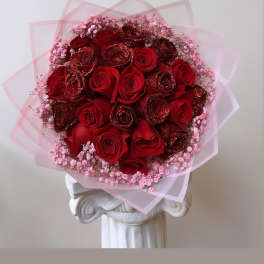 Bouquet of red roses with pink baby's breath and translucent pink wrap