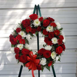 Red and white floral wreath on a standing easel with a red bow
