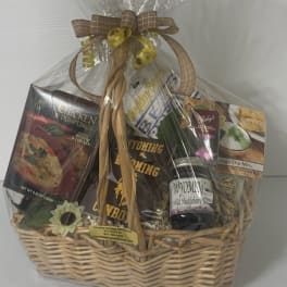 Gift basket with packaged food items in a wicker basket wrapped in cellophane