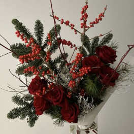 Red roses and berry branches in a clear glass vase