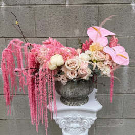 Pink floral arrangement in a stone urn with cascading blooms