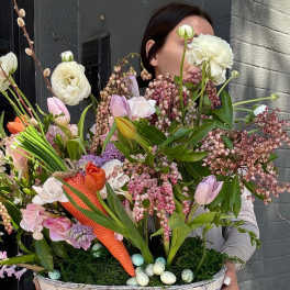Large spring bouquet in a woven basket with pastel flowers and speckled eggs