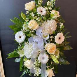 White floral standing spray with roses, gerberas, and hydrangea on an easel