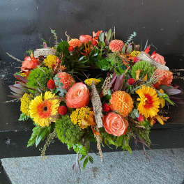 Circular floral wreath with orange and yellow blooms on a dark surface