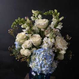 White roses and blue hydrangeas in a dark blue vase