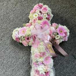 Cross-shaped floral arrangement with pink and white flowers and ribbon