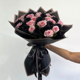 Bouquet of pink and black roses wrapped in black paper