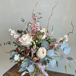 Tall bouquet of cream roses and pink flowers in a glass vase