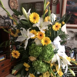 Large standing floral spray with white lilies, yellow daisies, and green hydrangea